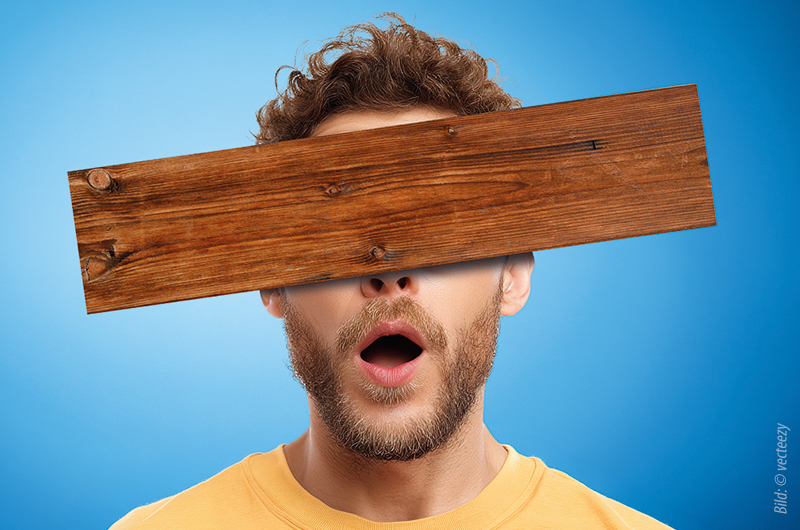 Mann mit offenem Mund und gelbem Pulli hat ein Brett vor dem Kopf